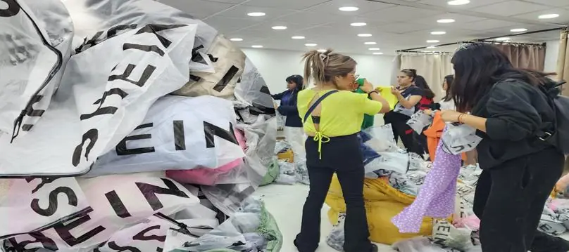Grupo de revendedores revisando prendas empaquetadas mientras aprenden como comprar pacas de Shein.